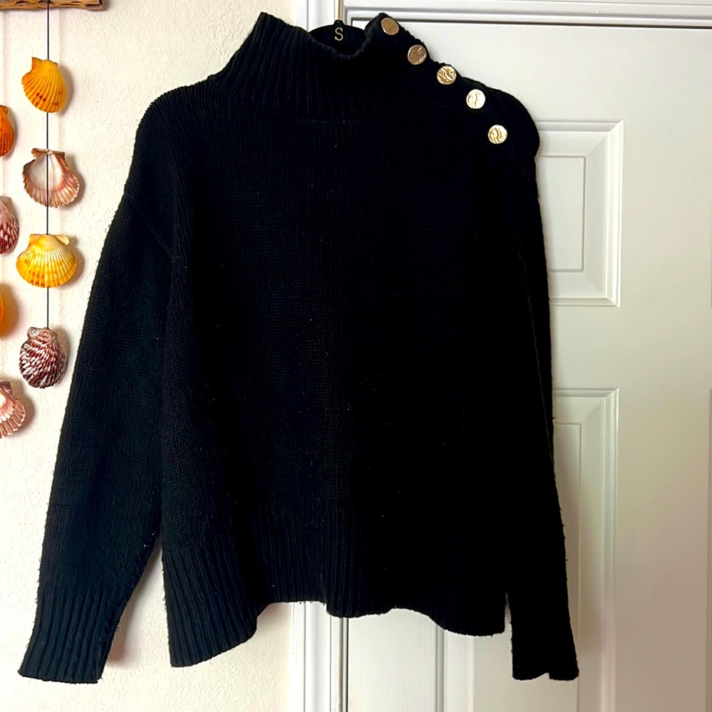 Black sweater with gold coins on one side.